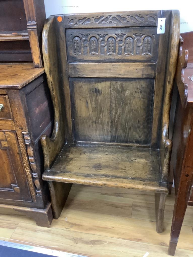 An 18th century style narrow oak panelled wing back settle